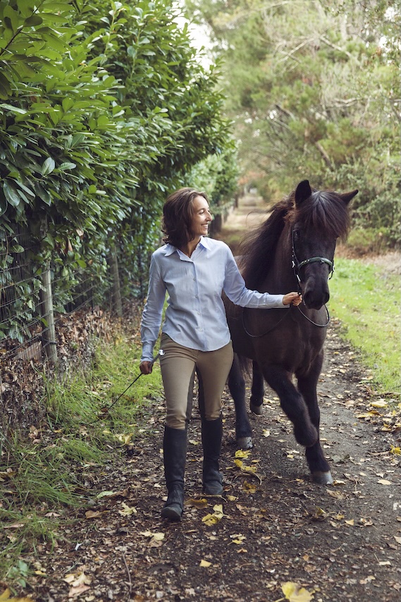 An Icelandic horse and its handler on a leafy path